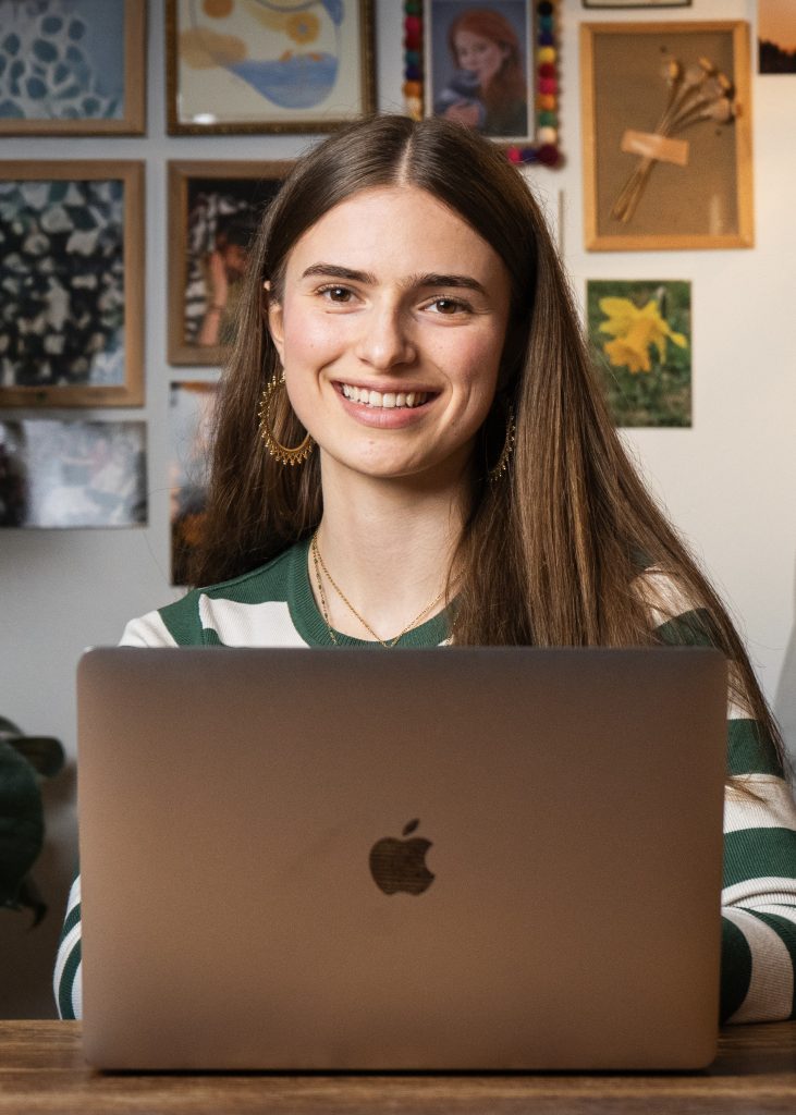 Eine junge Frau mit langen Haaren sitzt vor dem PC