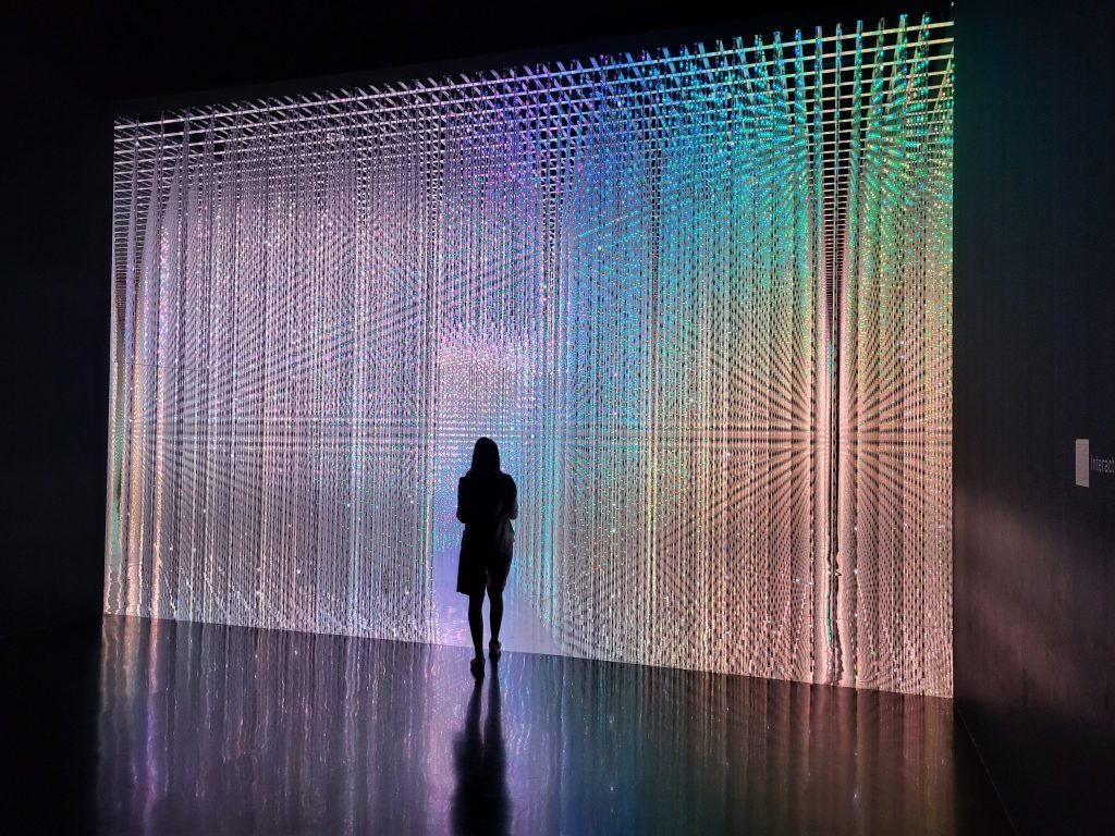 Symbolbild zu den Möglichkeiten der digitalen Welt. Eine Person läuft auf eine bunte LED-Kunstinstallation in Singapur zu.