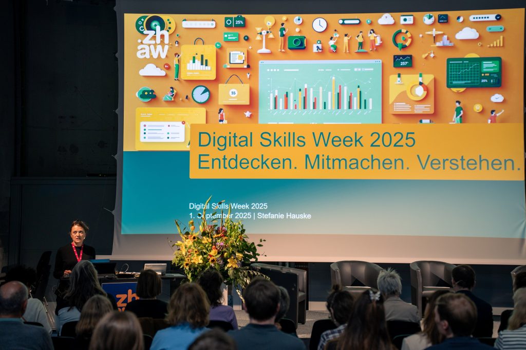 Foto der Bühne an der Digital Skills Week mit Stefanie Hauske am Rednerpult, im Vordergrund das Publikum.