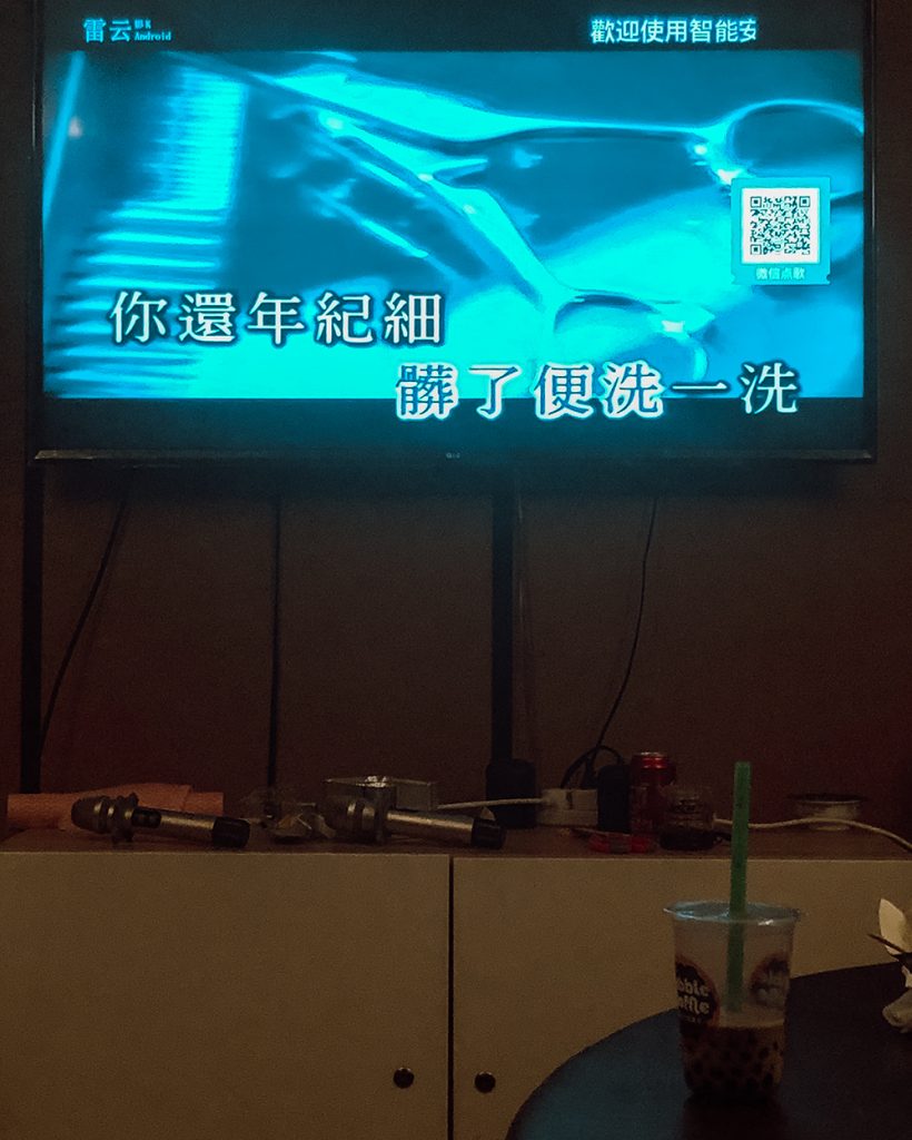 Karaoke machine. Tv screen and microphones with bubble tea on the table.