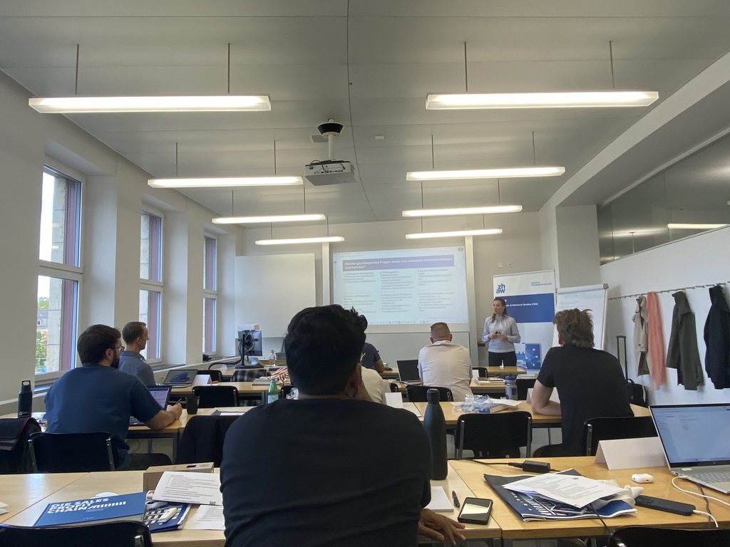 Seminarraum des CAS Sales mit Teilnehmenden und Dr. Janina-Vanessa Schneider am Präsentationsbildschirm