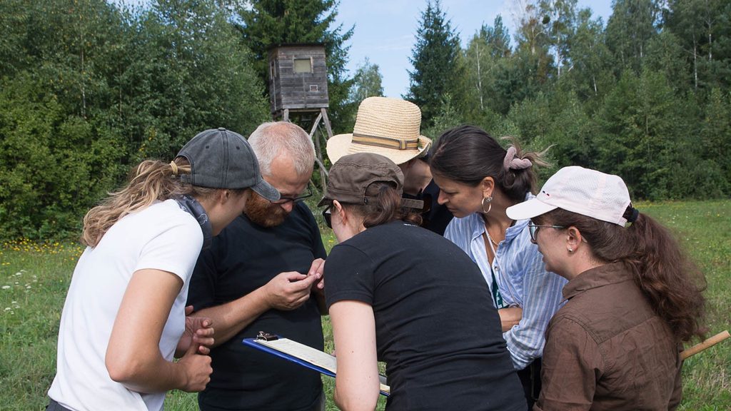 Studierende und Dozierende der Summer School «Biodiversity Monitoring» untersuchen gemeinsam einen Pflanzenfund auf einer Wiese in Białowieża, Polen.